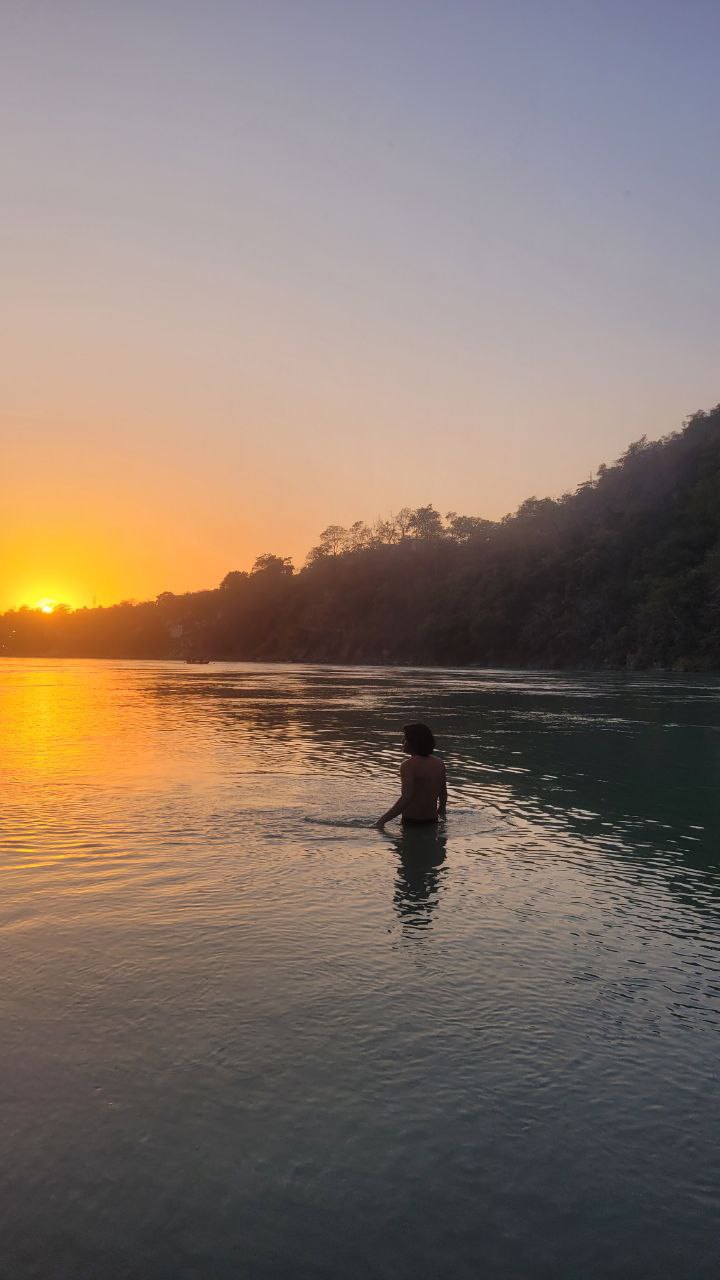Person standing in Ganga river at sunrise