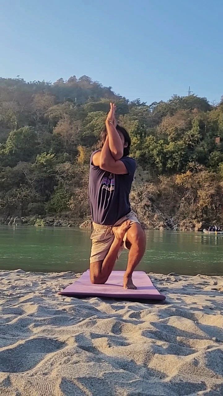Person performing Vatayanasana (Horse Face Pose) by the Ganga with full body visible