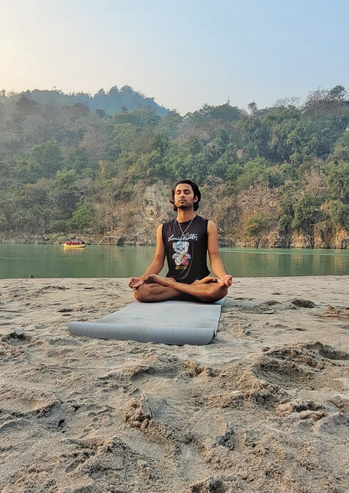 Person in meditation pose by the Ganga river
